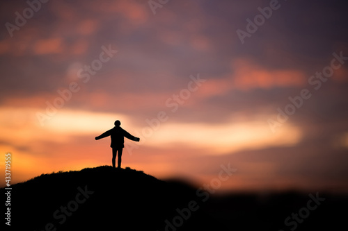 Silhouette of young traveler and backpacker watched the beautiful sky at sunset alone on top of the mountain. He enjoyed traveling and was successful when he reached the summit.