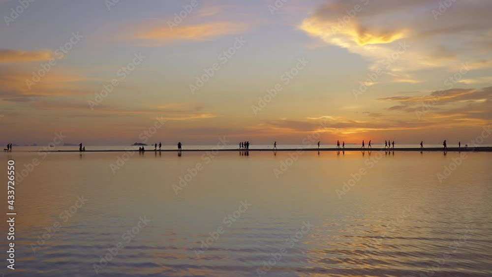 People Silhouette Walking on the Sand Bank at Beautiful Sunset with Orange Sky, Thailand. People Silhouette Walking on the Sand Bank at Beautiful Sunset with Orange Sky, Thailand.