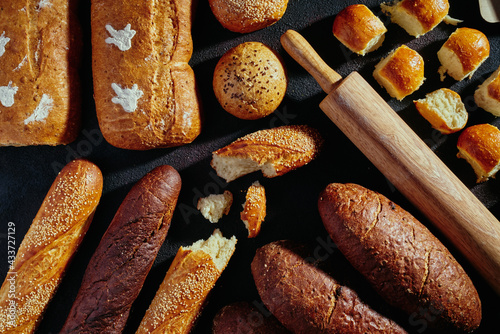 Pattern of bread. Bread assortment: baguettes, buns, loaves, dark and light bread. Delicious freshly baked bread on dark rustic background. top view. close up