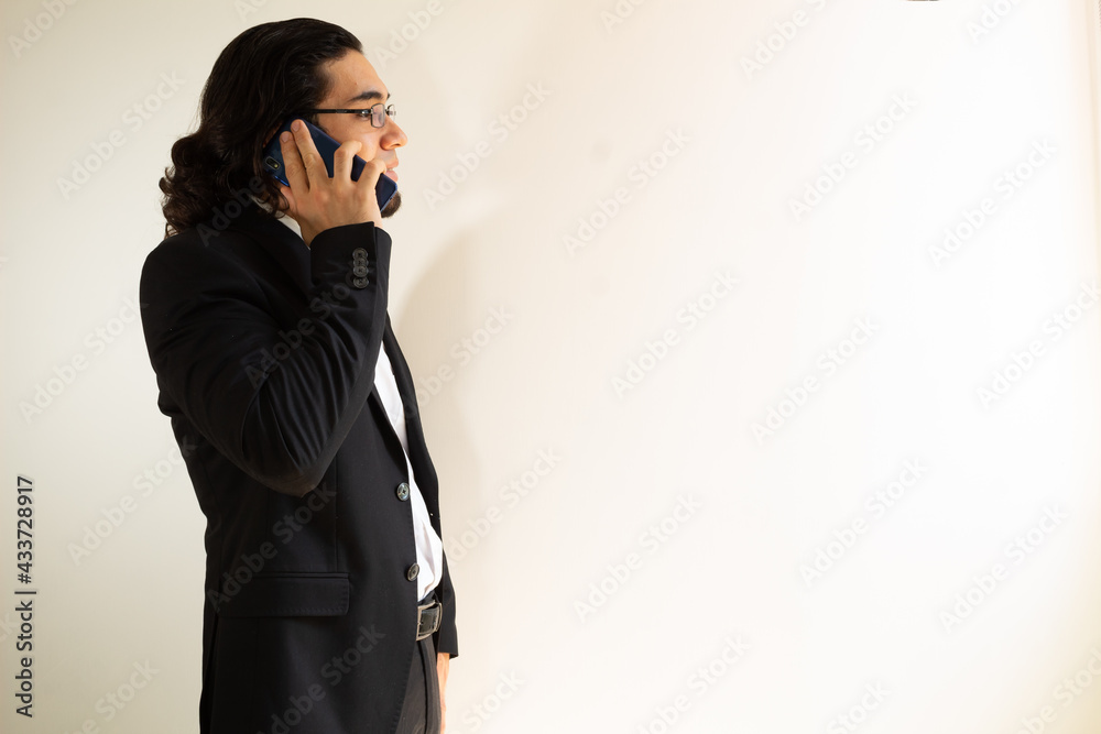 Hispanic man in black suit using a smartphone on a white background Hispanic man in black suit using a smartphone on a white background