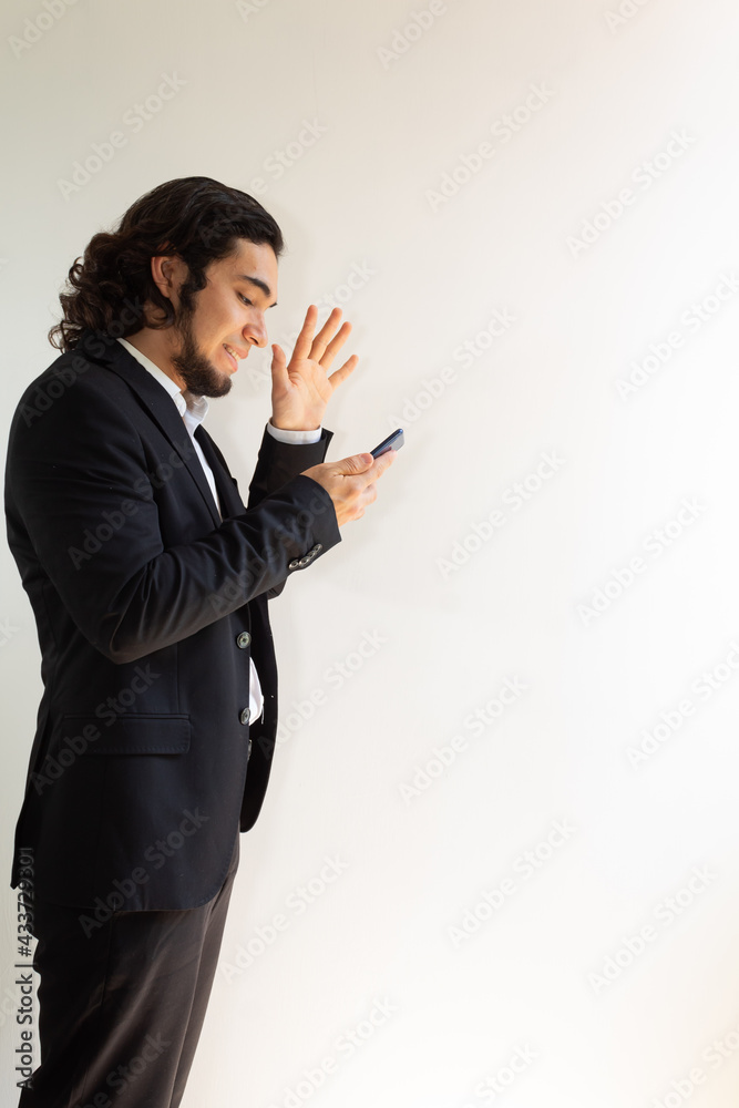 Hispanic man in black suit using a smartphone on a white background Hispanic man in black suit using a smartphone on a white background