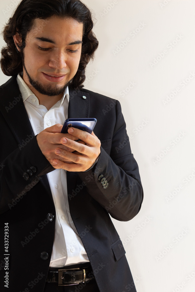 Hispanic man in black suit using a smartphone on a white background Hispanic man in black suit using a smartphone on a white background