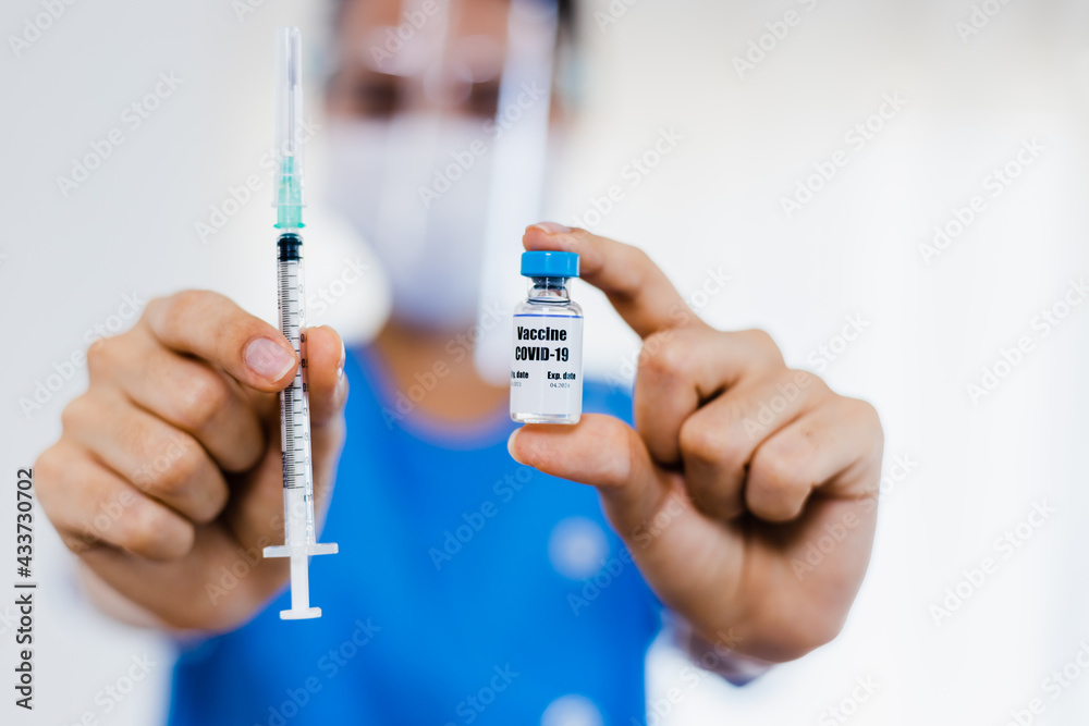 Close up woman doctor holding syringe and bottle of vaccine ready for injection to patient people in medical mask. Covid-19 or coronavirus vaccine Close up woman doctor holding syringe and bottle of vaccine ready for injection to patient people in medical mask. Covid-19 or coronavirus vaccine