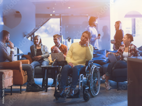 Portrait of disabled businesswoman in a wheelchair in front of her diverse business team at office