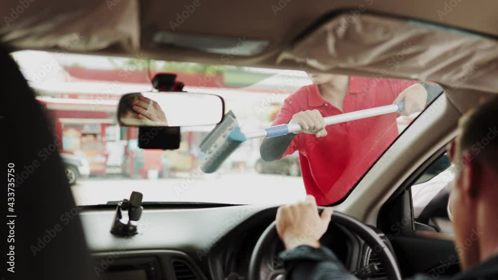 smiling gas station attendant collecting payment through window from young man at driver seat paying with credit card or qr code chatting with him. smiling gas station attendant collecting payment through window from young man at driver seat paying with credit card or qr code chatting with him.