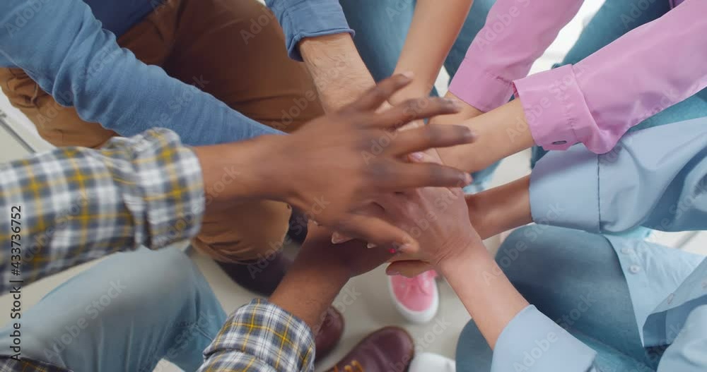 Multiracial people putting hands together in team meeting