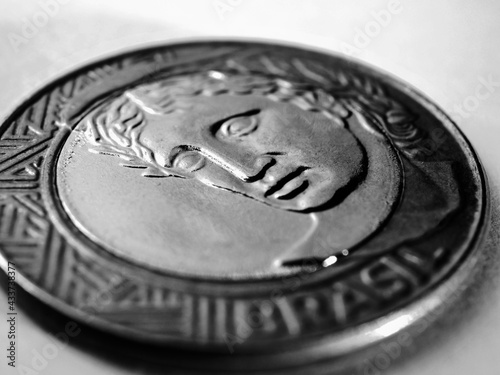 Brazilian 1 real coin close-up. Dramatic black and white illustration about money, economy and public finances in Brazil. The reverse of the coin with the Figure of the Republic. Macro