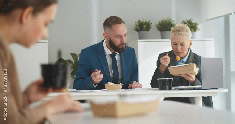 Business people having takeaway lunch and discussing work in office Business people having takeaway lunch and discussing work in office