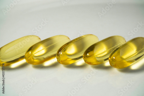 Cod liver oil capsule pill stack together. Close up fish oil pills on the white plate