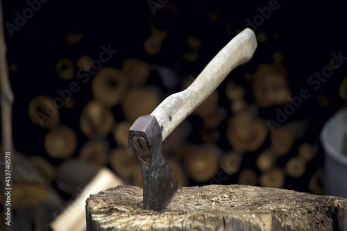 the axe is stuck in a log near the woodpile