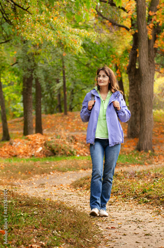 Middle aged active caucasian female model with backpack walk in woods autumn time Middle aged active caucasian female model with backpack walk in woods autumn time