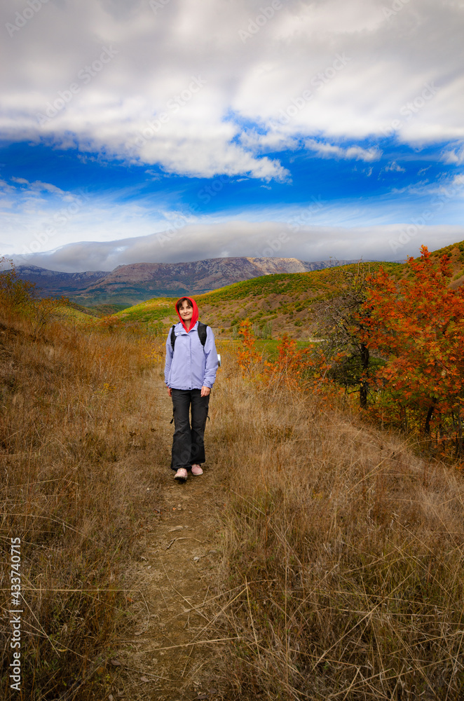 Middle aged active caucasian female model with backpack walk in mountains autumn time