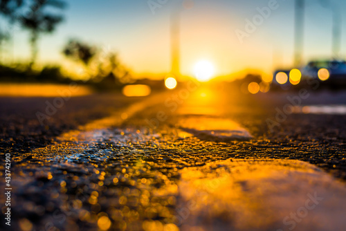 Sunset after rain, the headlights of the approaching cars on the highway. Close up view from the level of the dividing line