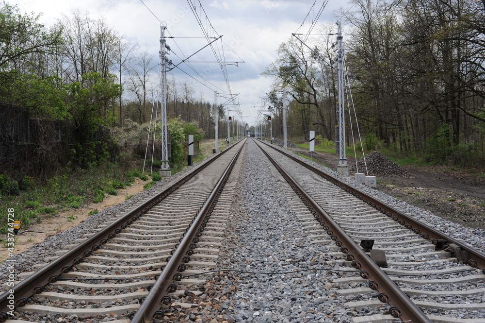 Railroad tracks for trains  with steel rails and gravel creating straight perspective lines till horizon