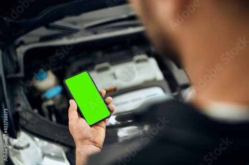 Close-up of auto repairman using smart phone while working in a workshop.