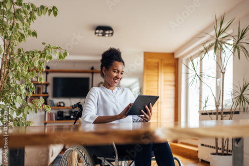 Smiling black woman using digital tablet at home. photo