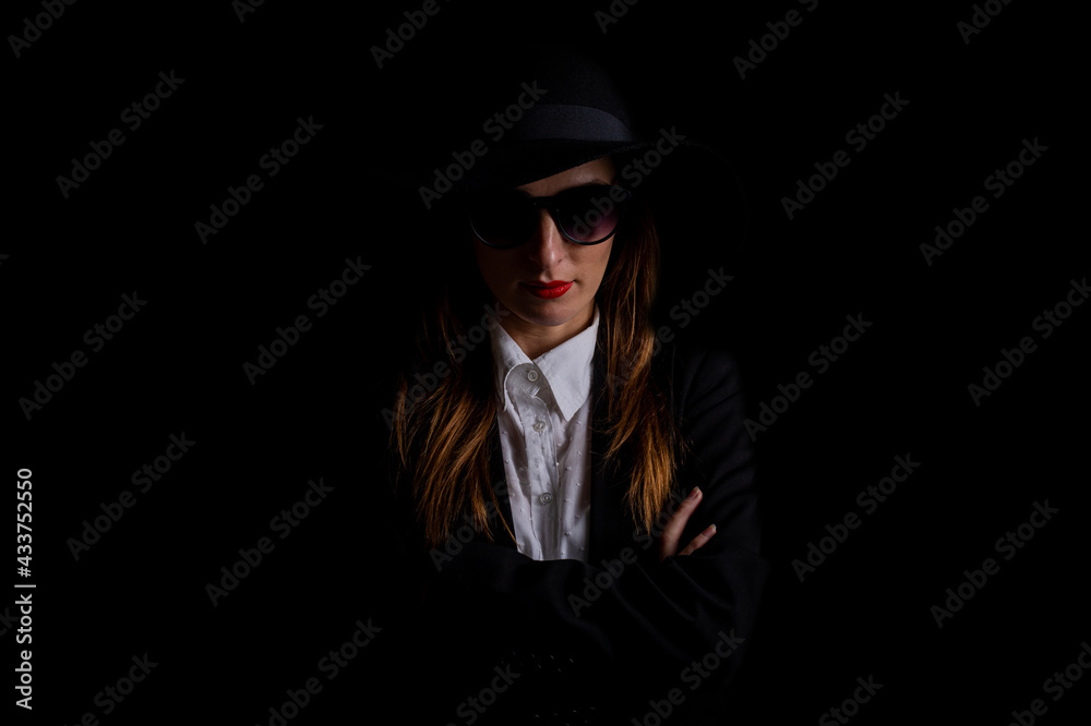 beautiful business elegant woman in a hat, glasses in the dark on a black background beautiful business elegant woman in a hat, glasses in the dark on a black background