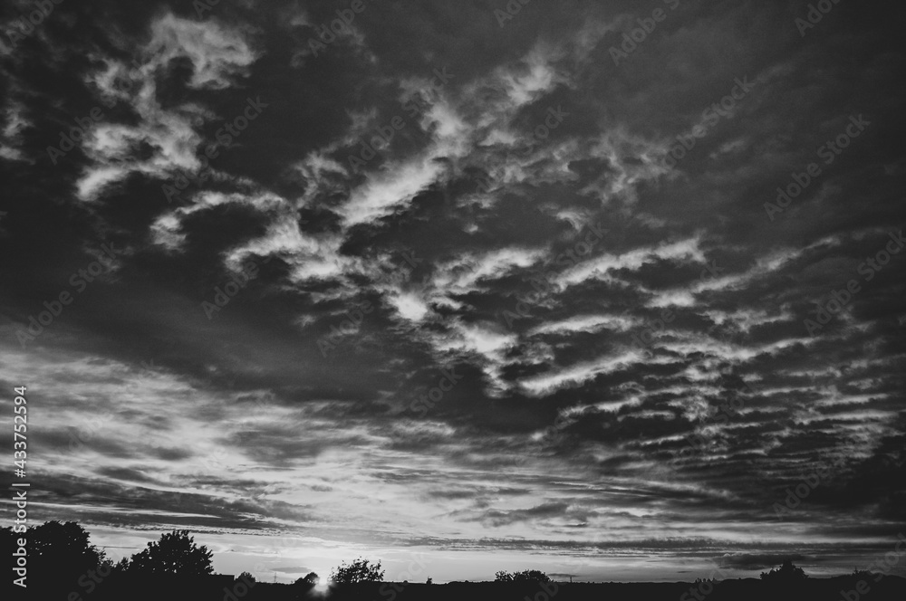 Fototapeta premium Under lit clouds at sunset in black and white 