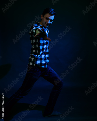 A young man in a studio on a dark background with a multicolored light © ISliM