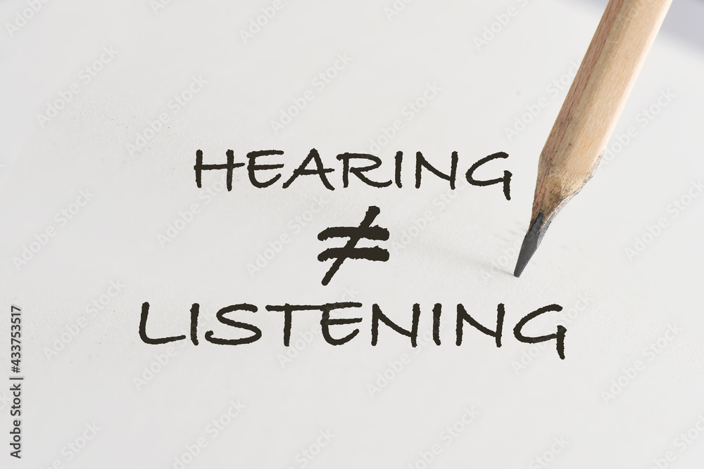 Fototapeta premium Hearing not equal listening written on white paper with pencil. Communication with understanding concept and soft skill idea