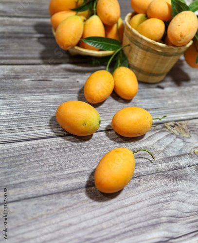 Bunch of Sweet yellow Marian plum or plum mango on the wood table. Seasonal fruit in Thailand for February - April 