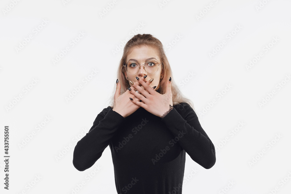 Oops. Shocked young woman clothed in black casual clothes is holding her hands over her mouth because of shock Oops. Shocked young woman clothed in black casual clothes is holding her hands over her mouth because of shock