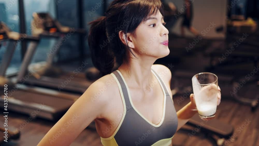 Young beautiful woman asian running on a treadmill at gym. Fitness and healthy lifestyle concept. Side view of girl in sportswear jogging exercise. 