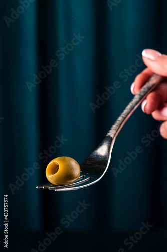 one green olive on a fork