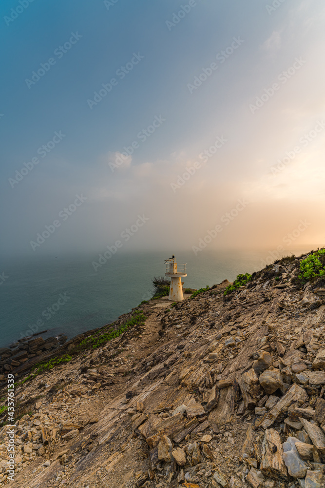 Sunrise by the sea with a lighthouse on the cliff