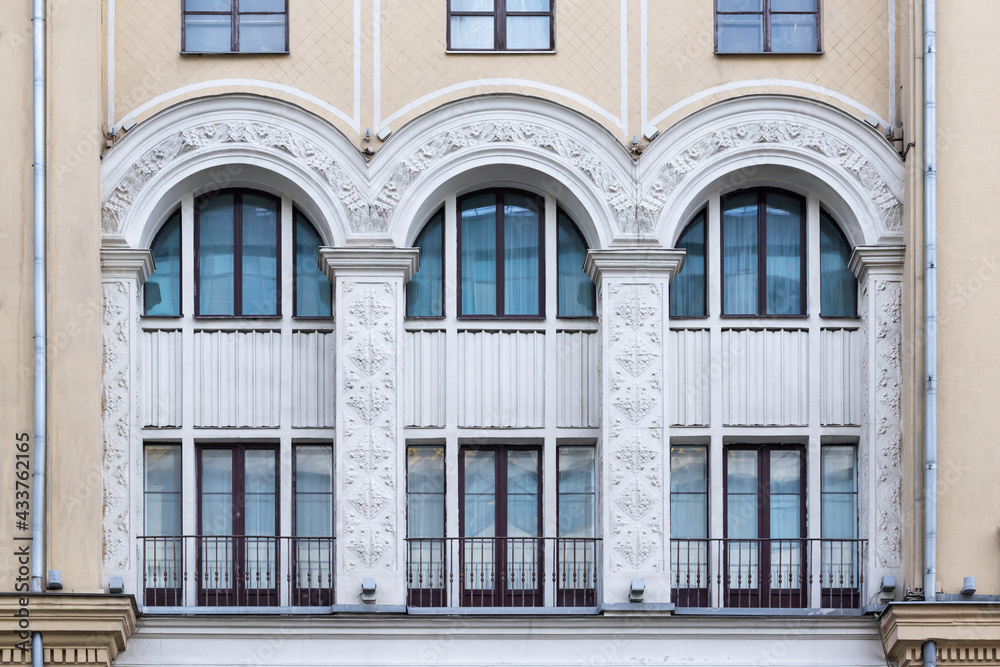 Soviet architecture classical facade building front view. Three big arched windows decorated with stucco moulding architectural details.