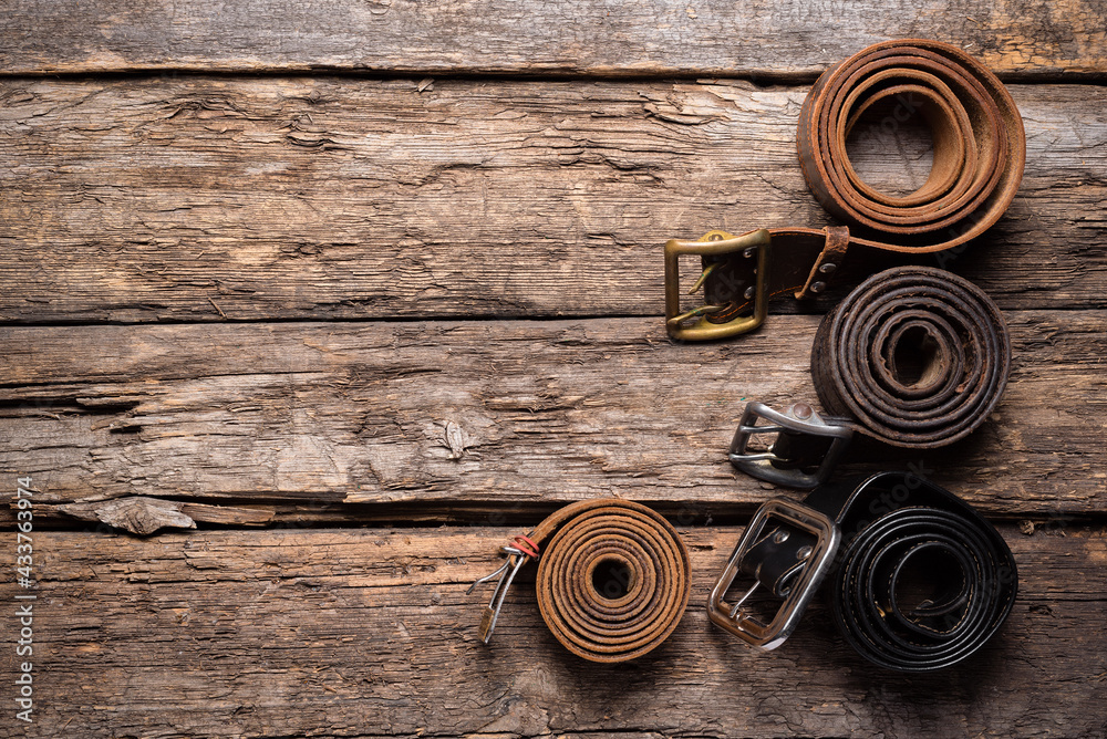Fototapeta premium Old retro style male belts on the wooden table flat lay background with copy space.