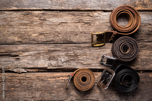 Old retro style male belts on the wooden table flat lay background with copy space.