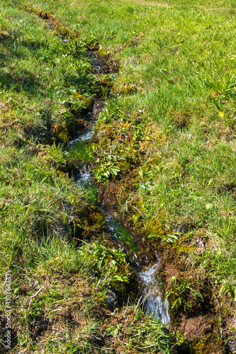 Stream on a grass meadow with running water