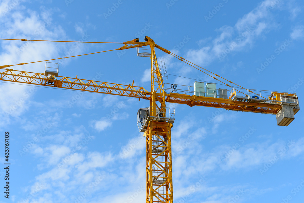 Construction tower crane with cab on blue sky background