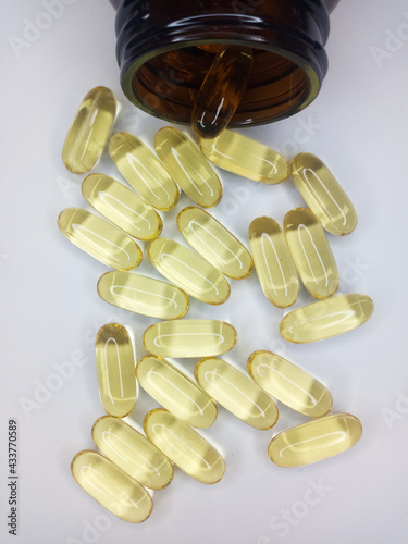 Transparent capsules of light yellow color poured from the bottle