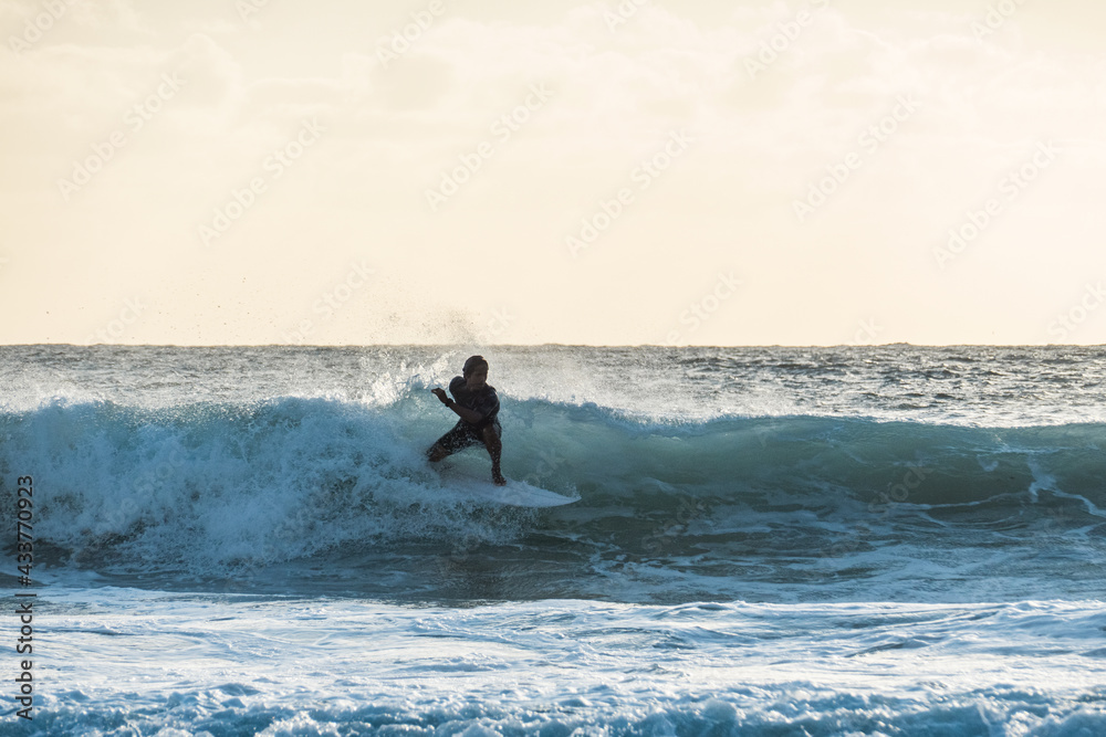 Young surfer riding a wave at sunset Young surfer riding a wave at sunset