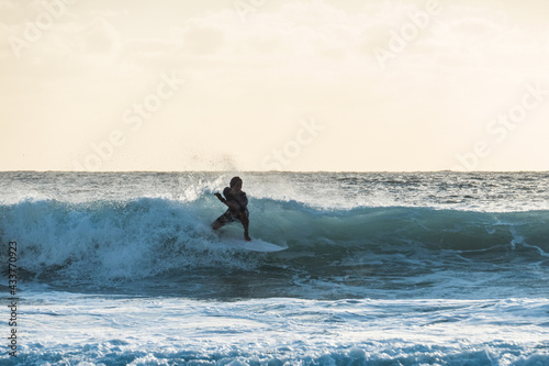 Young surfer riding a wave at sunset