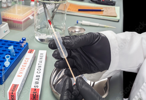 Police expert extracts traces of blood in a swab for analysis in the laboratory scientist, conceptual image