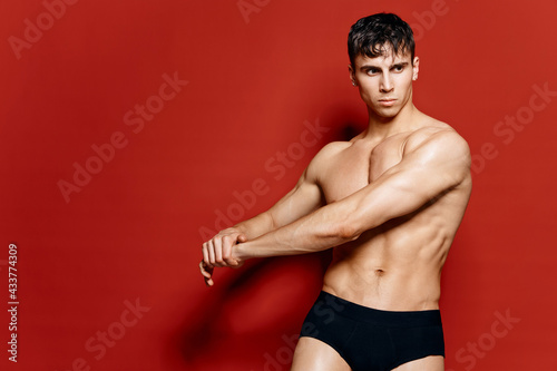sexy athletes with a naked torso in black panties turned his arms to the side 