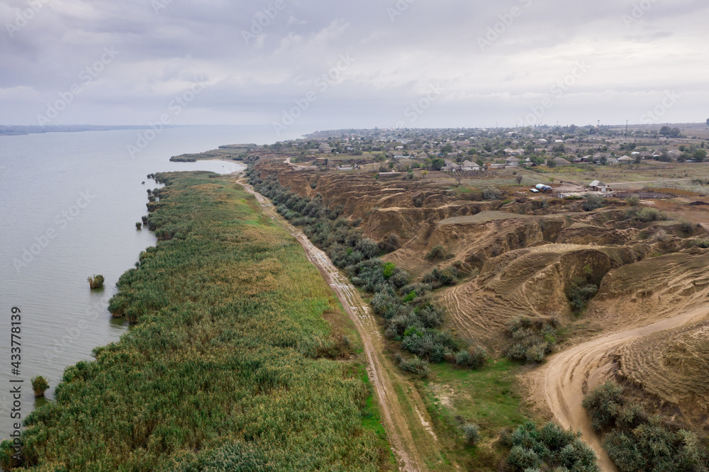 Aerial view of a path along huge lake with beautiful sand dunes and green shore