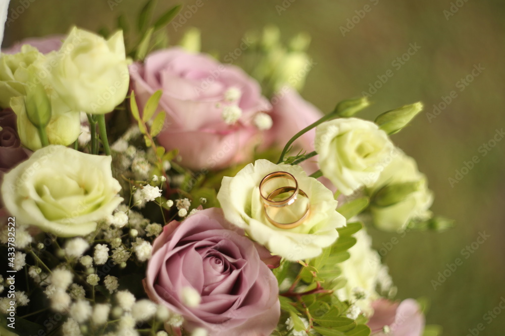 Golden wedding rings on a bride's bouquet. Marriage concept.