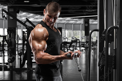 Muscular man working out in gym doing exercise for biceps, strong male bodybuilder