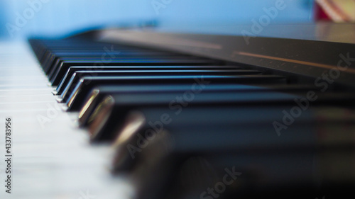 Vue rapprochée sur les touches d'un piano, dans une pièce bleuâtre