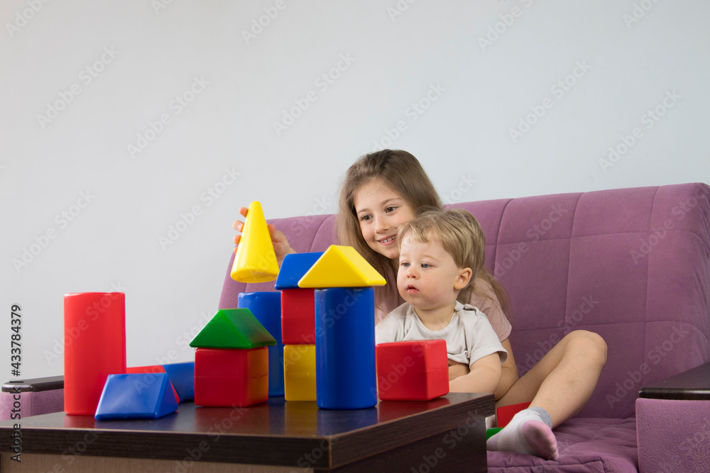 boy and girl play with colorful figures cone cubes build a house tower, brother and sister have fun boy and girl play with colorful figures cone cubes build a house tower, brother and sister have fun