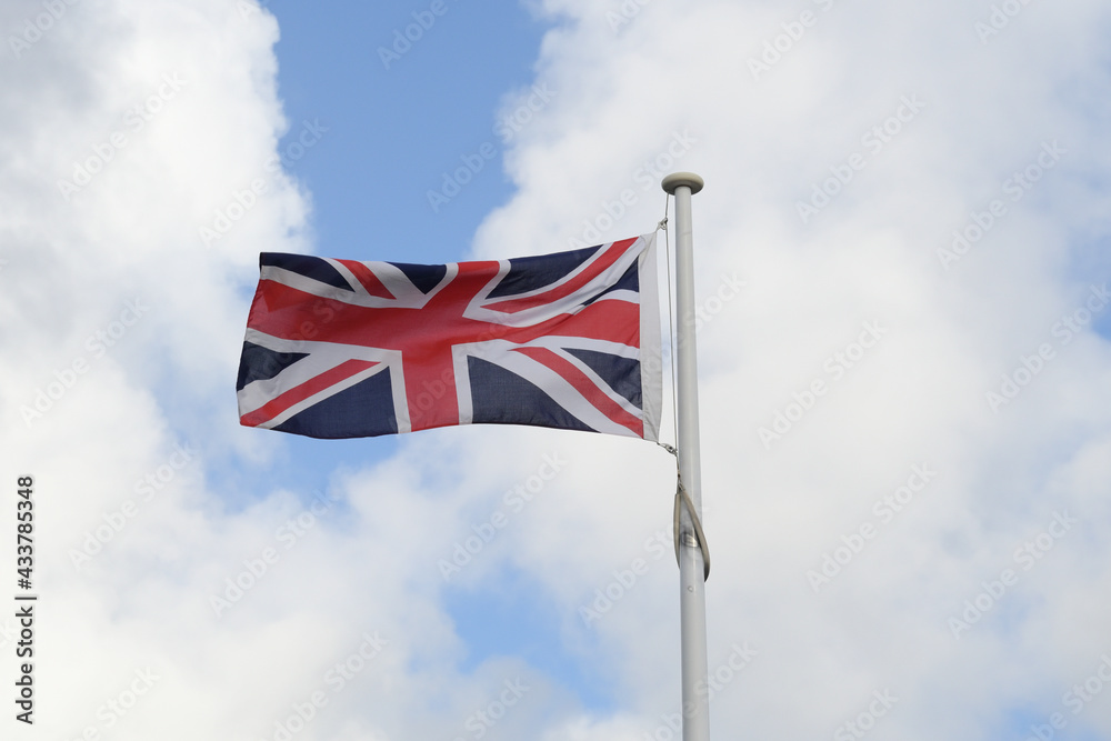 The Union Jack, or Union Flag, flying on a windy day, with bright blue sky and white clouds in the background The Union Jack, or Union Flag, flying on a windy day, with bright blue sky and white clouds in the background