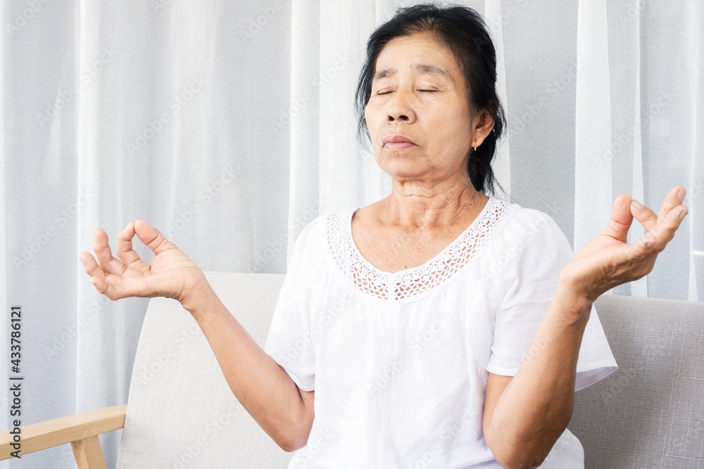 elderly Asian woman doing yoga and meditating peaceful indoors elderly Asian woman doing yoga and meditating peaceful indoors