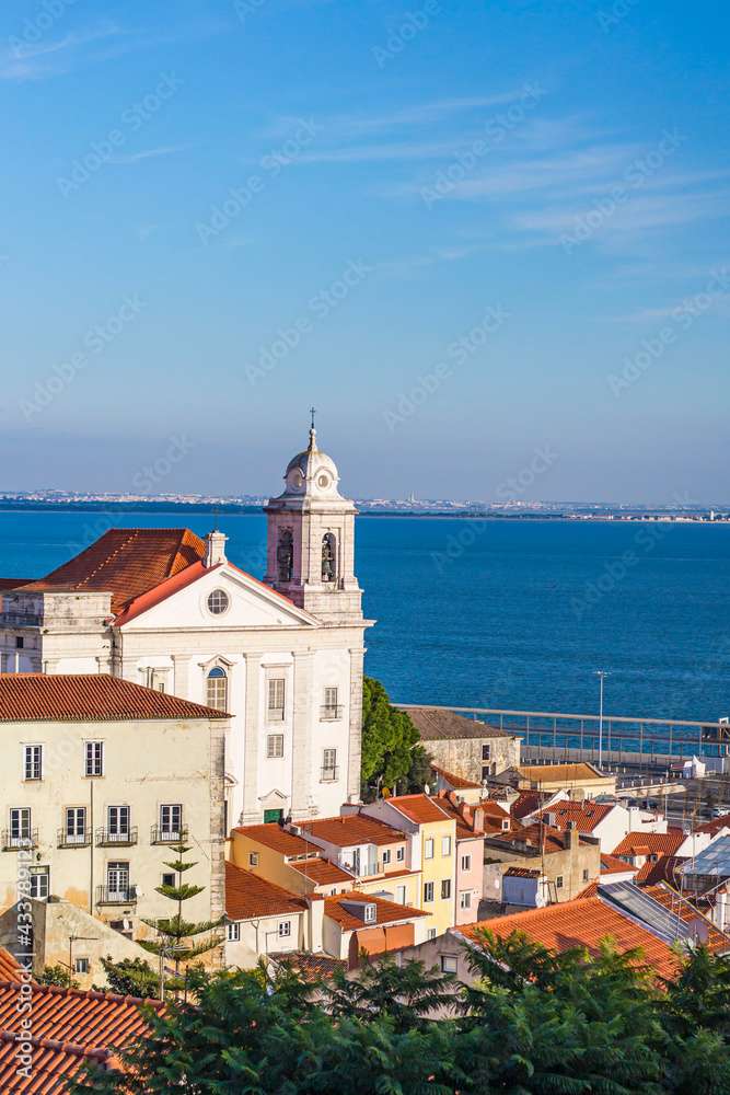 View of white houses with brown roof tiles against the sea in Lisbon, Portugal alfama district