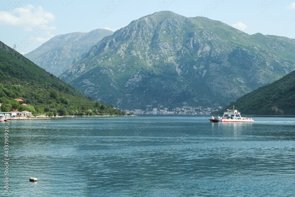 Ferry boat carrying cars between the two banks of Bay of Kotor, or Kotorska Boka, in the afternoon in the waters of the Adriatic sea. The gulf of Kotor  is the most iconic landmarks of Montenegro...