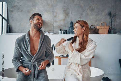Konstfotografi Loving young couple in bathrobes laughing while doing morning routine