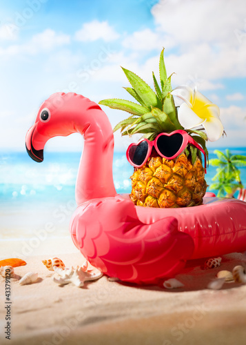 Pink inflatable flamingo and hipster pineapple in sunglasses..Summer pool float party idea. Summer creative concept. photo